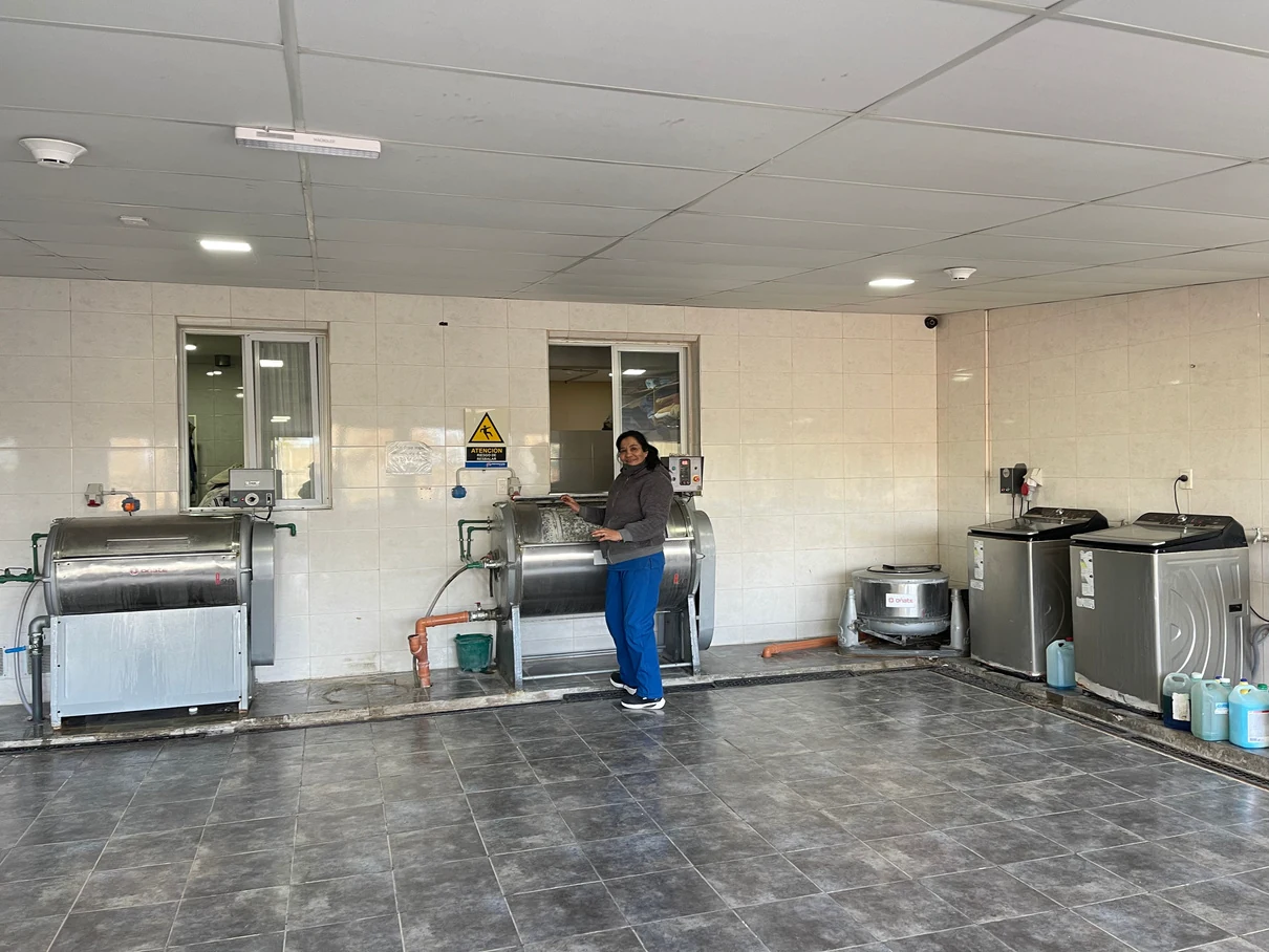 Lavandería del Hogar y una trabajadora junto a las máquinas